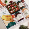 White box filled with a holiday feast of chocolate caramels, cornbread and gourmet jams and sauce.